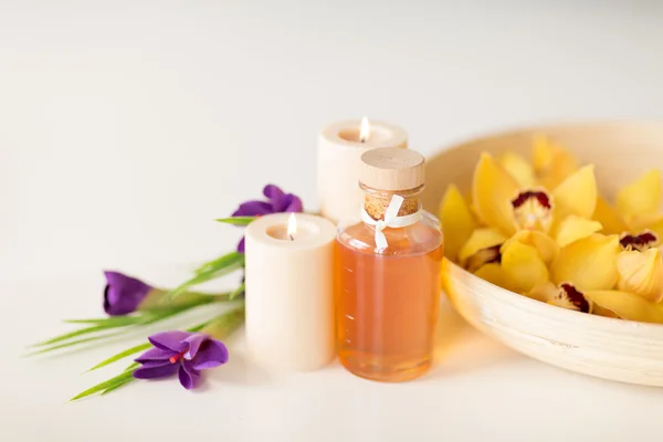 Flores de orquídea en cuenco, aceite, velas e iris —  Fotos de Stock