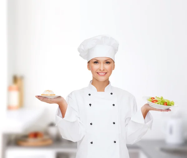 Chef féminine souriante avec salade et gâteau dans des assiettes — Photo