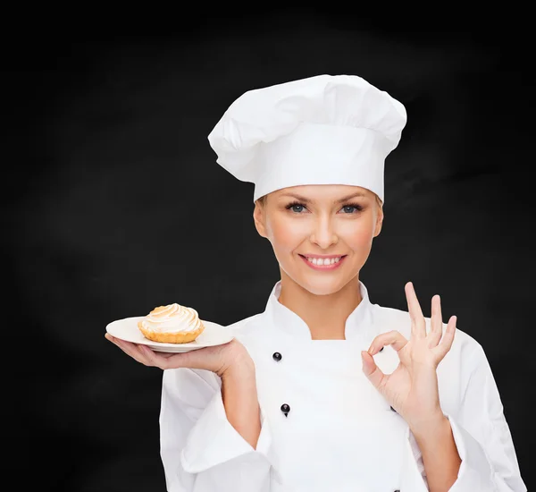 Cuoca sorridente con torta sul piatto — Foto Stock