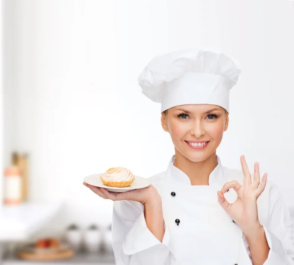 Chef feminino sorridente com bolo no prato — Fotografia de Stock