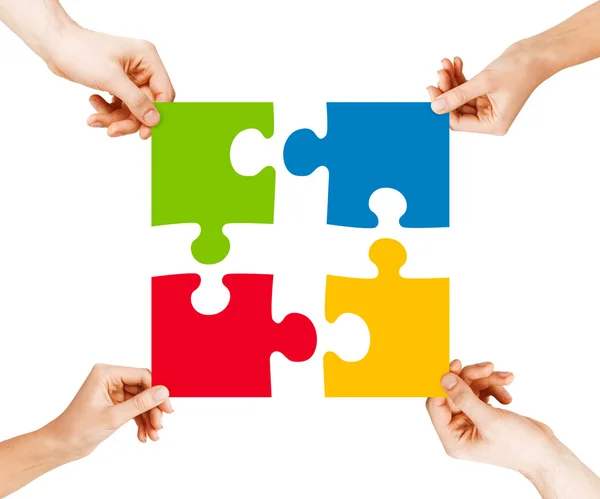 Quattro mani che collegano pezzi puzzle — Foto Stock
