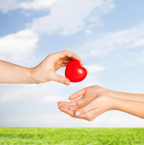 Man hand giving red heart to woman — Stock Photo, Image