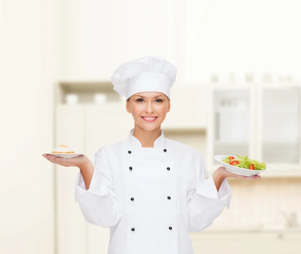 Chef féminine souriante avec salade et gâteau dans des assiettes — Photo