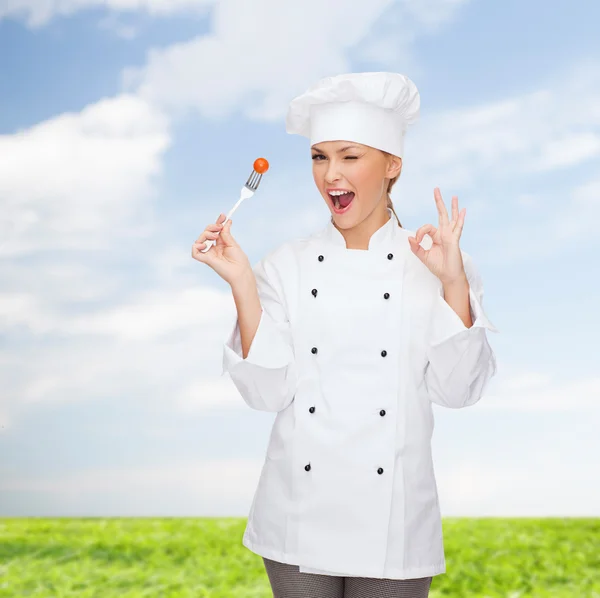 Chef feminino sorridente com garfo e tomate — Fotografia de Stock