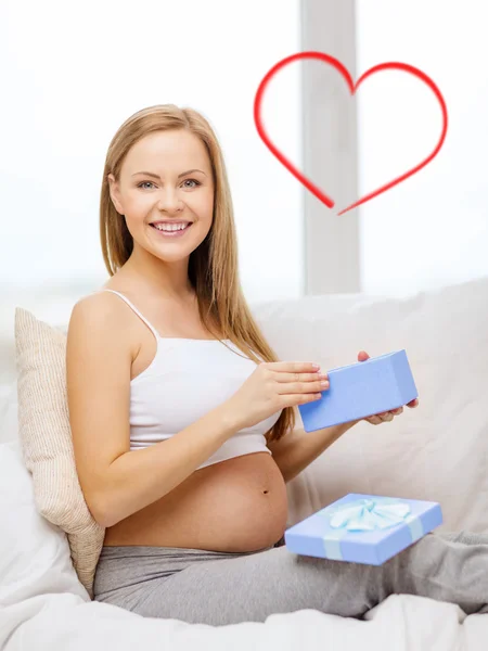 Smiling pregnant woman opening gift box — Stock Photo, Image