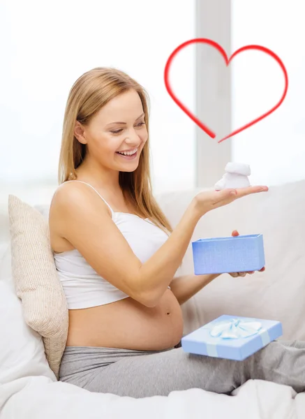 Mujer embarazada sonriente con caja de regalo y botas —  Fotos de Stock