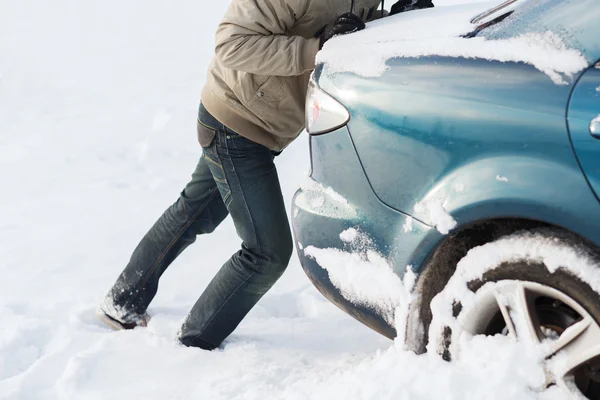 Zbliżenie mężczyzna popychając samochód utknął w śniegu — Zdjęcie stockowe