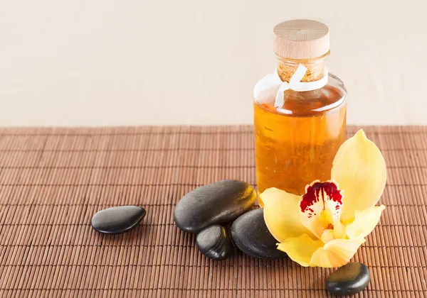 Óleo essencial, pedras de massagem e flor de orquídea — Fotografia de Stock