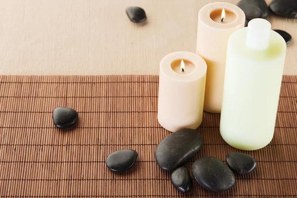 Shampoo bottle, massage stones and candles — Stock Photo, Image