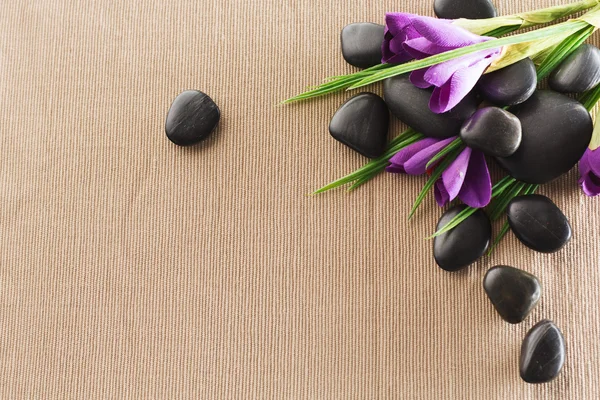 Massage stones with flowers on mat — Stock Photo, Image