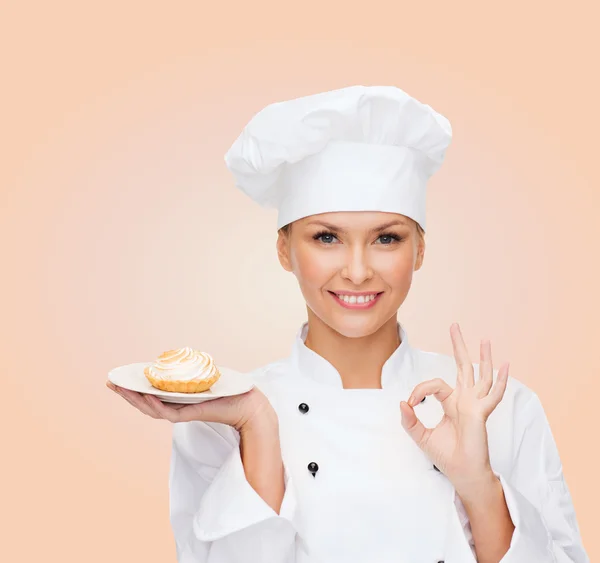 Lächelnde Köchin mit Kuchen auf Teller — Stockfoto