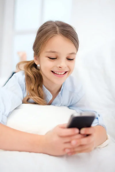 Lachende meisje met smartphone thuis — Stockfoto