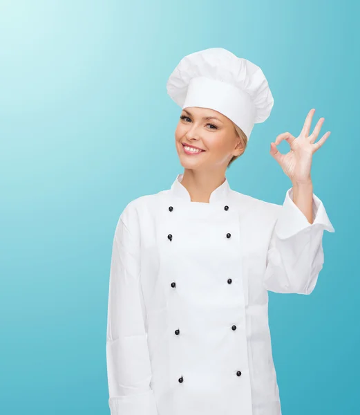 Smiling female chef showing ok hand sign Stock Picture