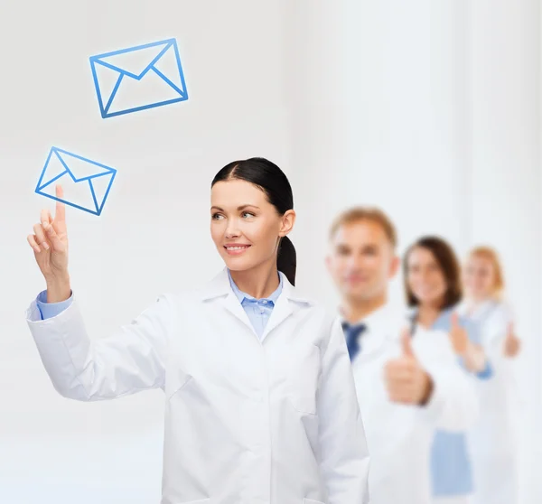 Médica sorridente apontando para envelope — Fotografia de Stock