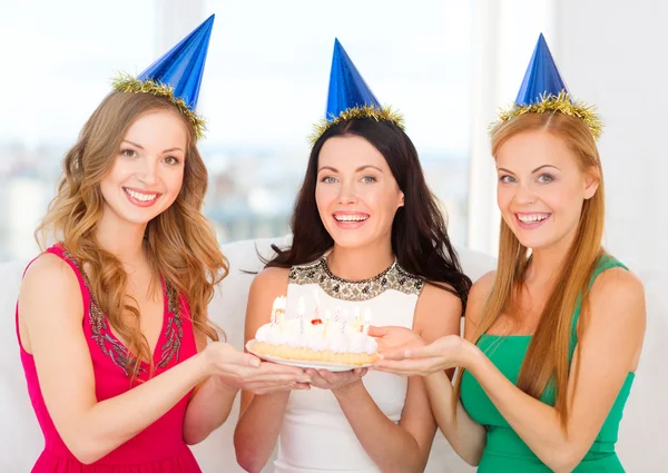 Tre donne che indossano cappelli che tengono la torta con le candele — Foto Stock