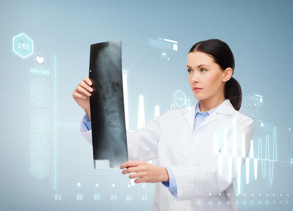 Serious female doctor looking at x-ray — Stock Photo, Image