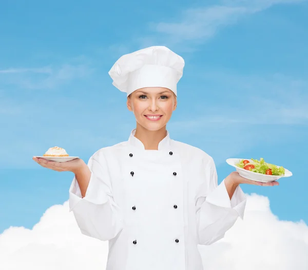 Chef sonriente con ensalada y pastel en platos —  Fotos de Stock