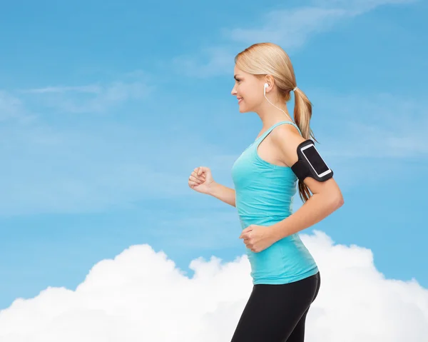 Mujer deportiva corriendo con smartphone y auriculares —  Fotos de Stock