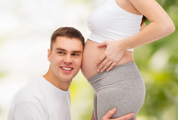 Père heureux écoutant le ventre de sa femme enceinte — Photo