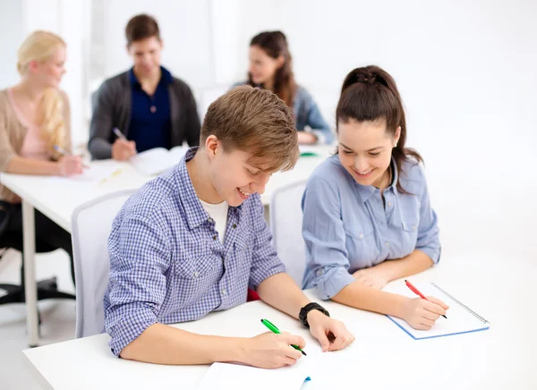 Usmívající se studenti s notebookem ve škole — Stock fotografie