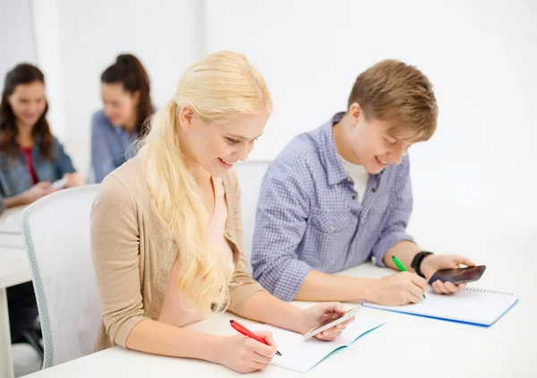 Lachende studenten met laptops op school — Stockfoto