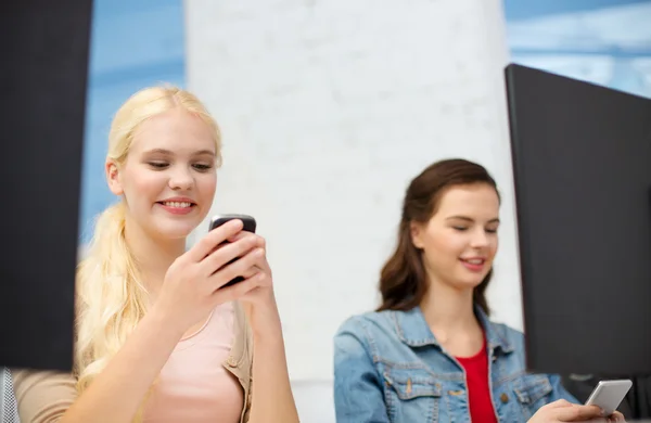 Deux adolescents avec smartphones en classe informatique Images De Stock Libres De Droits