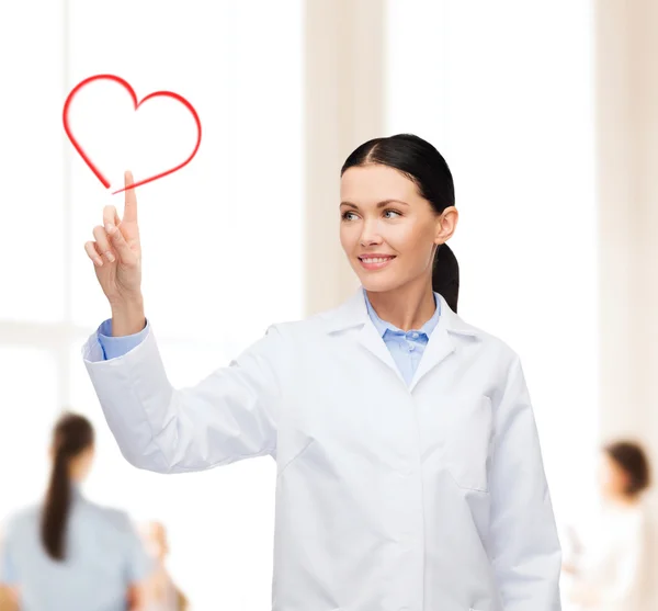Usmívající se žena doktor směřující k srdci — Stock fotografie