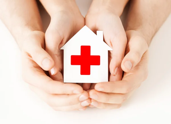 Hands holding paper house with red cross — Stock Photo, Image