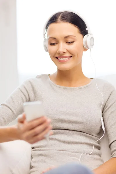 Mulher com smartphone e fones de ouvido em casa — Fotografia de Stock