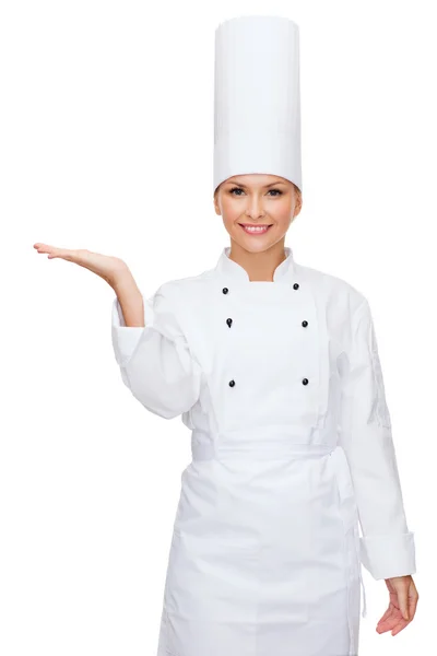 Leende kvinnlig kock håller något på handen — Stockfoto