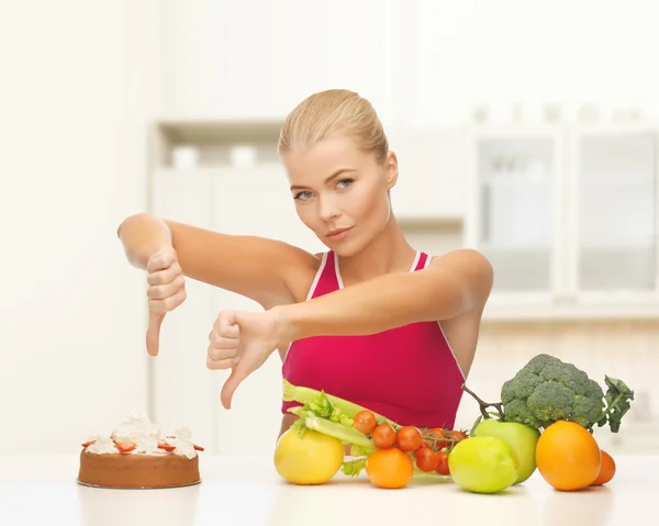 Woman with fruits showing thumbs down to cake — Stock Photo, Image