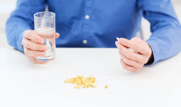 Male hand holding pill and glass of water — Stock Photo, Image