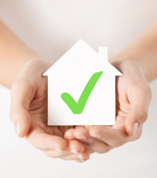 Mãos segurando casa com marca de verificação — Fotografia de Stock