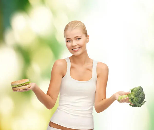 Kobieta z brokuły i hamburger — Zdjęcie stockowe