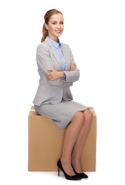 Mulher sorridente sentada na caixa de papelão — Fotografia de Stock