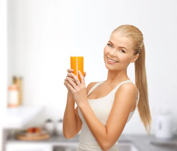 Mulher sorridente segurando vidro de suco de laranja — Fotografia de Stock