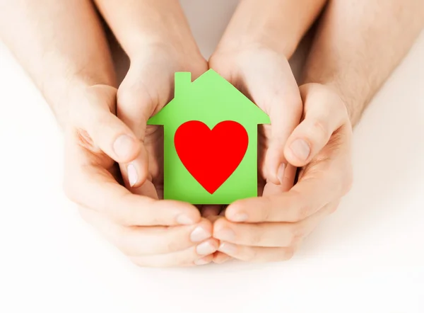 Un par de manos sosteniendo la casa de papel verde — Foto de Stock