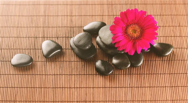 Massage stones with flower on mat — Stock Photo, Image