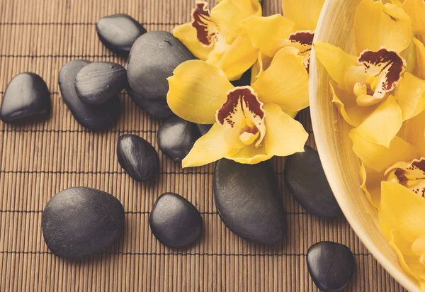Massage stones with orchid flowers on mat — Stock Photo, Image
