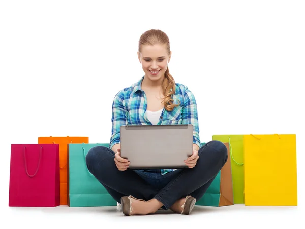 Chica sonriente con ordenador portátil comuter y bolsas de compras —  Fotos de Stock