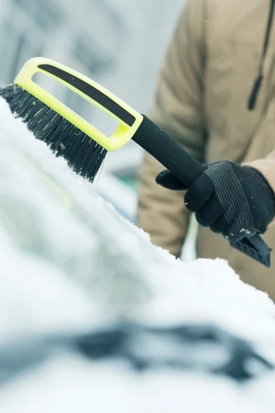 Homem limpando a neve do pára-brisas do carro com escova — Fotografia de Stock