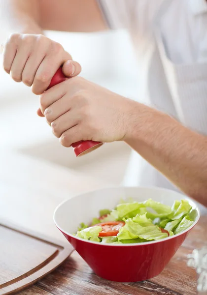 Close up of male hands flavouring salad in a bowl — Stock Photo, Image