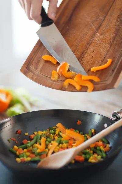 Close up van mannenhand paprika's toe te voegen aan wok — Stockfoto