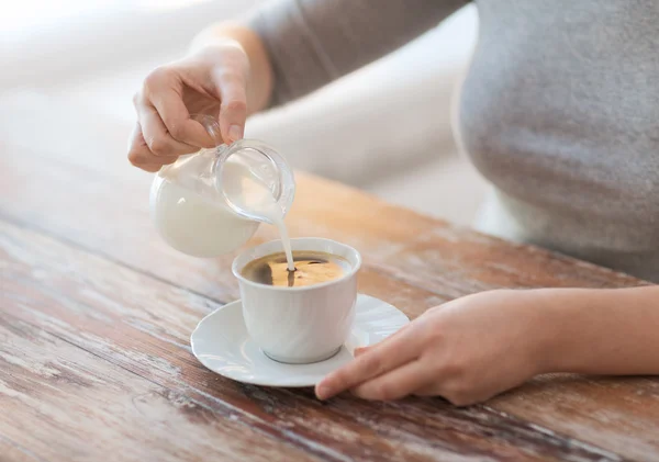 Primer plano de la hembra vertiendo leche en el café — Foto de Stock