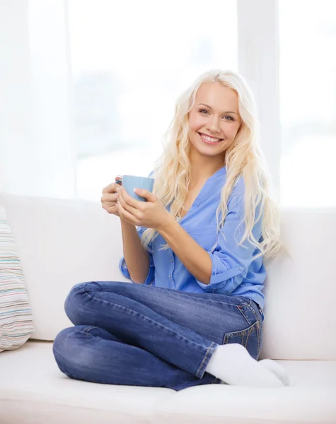 Sonriente chica joven con taza de café en casa — Foto de Stock