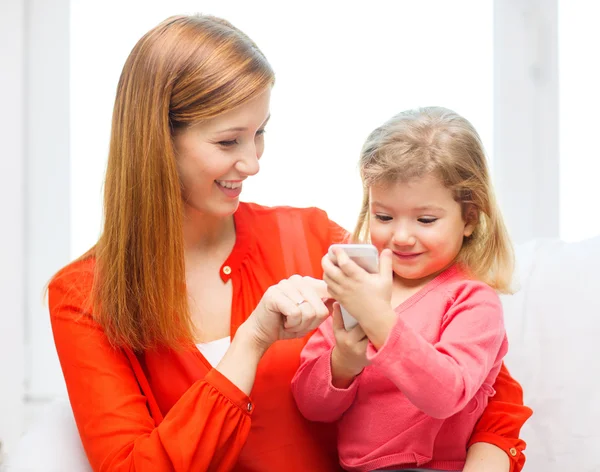 Šťastná matka a dcera s chytrým telefonem doma — Stock fotografie
