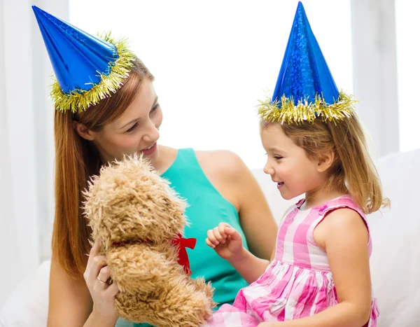 Mãe e filha em chapéus azuis com ursinho de pelúcia — Fotografia de Stock
