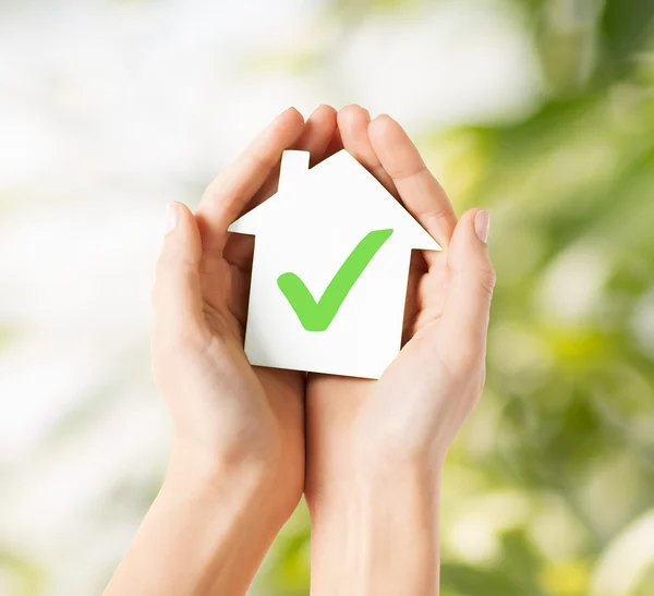 Mãos segurando casa com marca de verificação — Fotografia de Stock