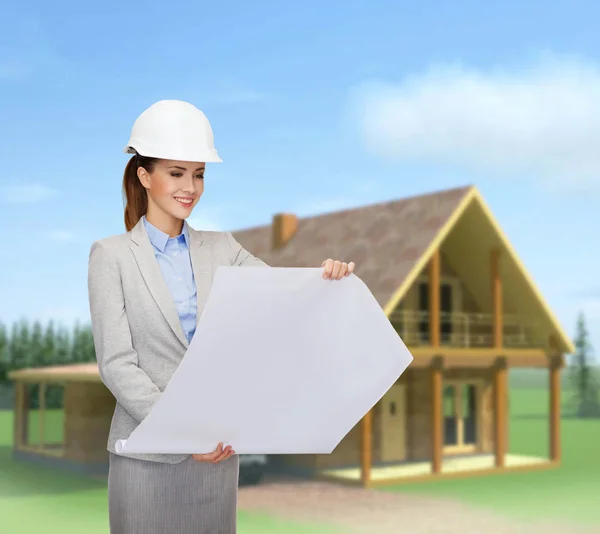 Arquitecto sonriente en casco blanco con planos — Foto de Stock