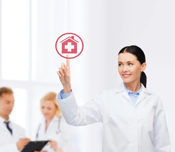 Una doctora sonriente señalando el signo del hospital —  Fotos de Stock